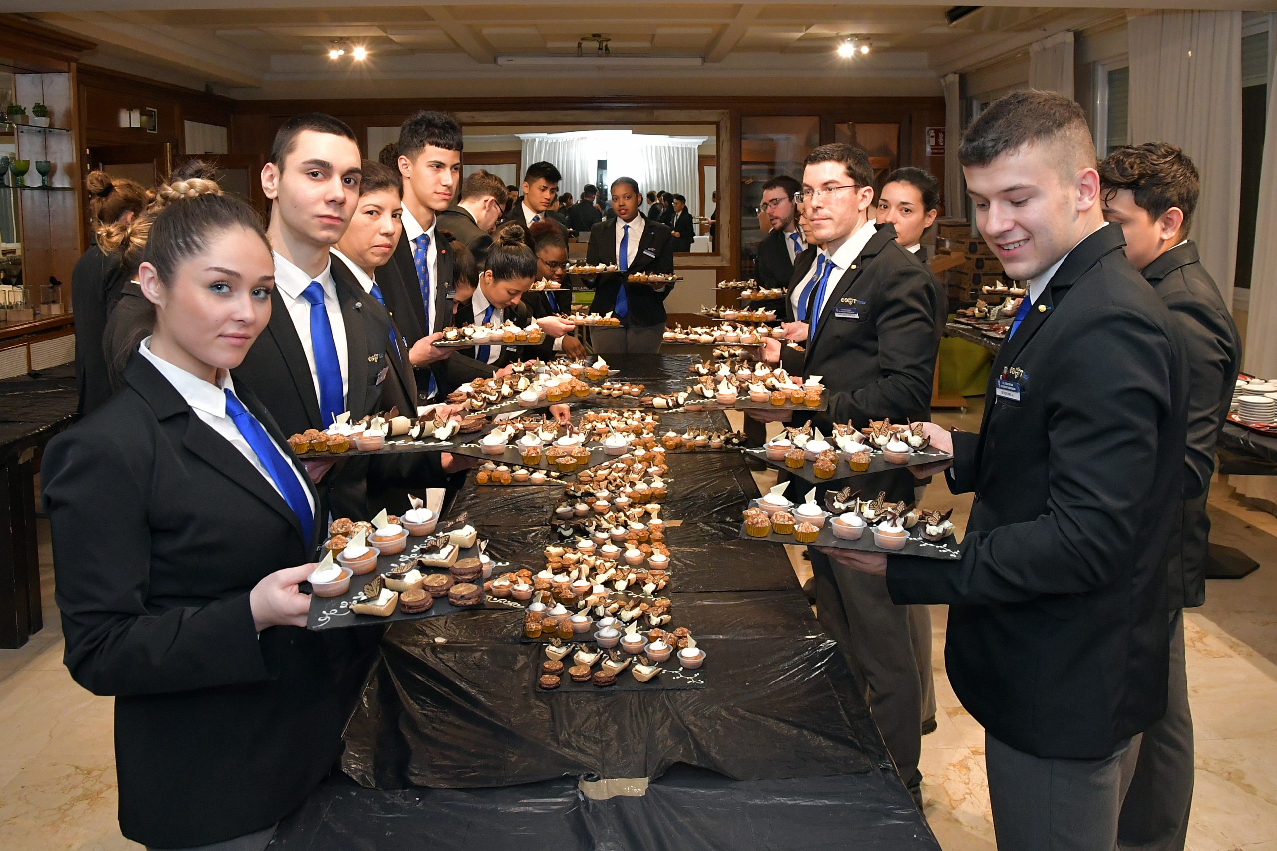 Chef y alumno de cocina de la escuela de hostelería con bandejas de canapés durante un servicio